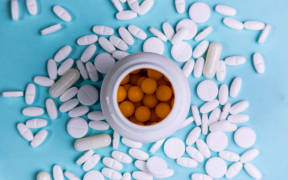 White scattered pills and a jar with yellow pills on a blue background