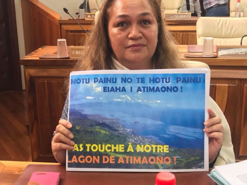 French Polynesian opposition politician Valentina Cross holds a poster expressing her opposition to a proposed floating island project.