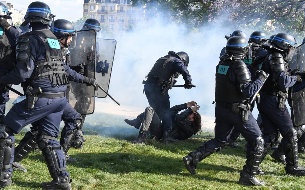 A protester reacts on the ground as a police officer stands over him  during clashes  on the sidelines of the annual May Day rally, marking International Workers' Day, in Paris on 1 May 2022.
