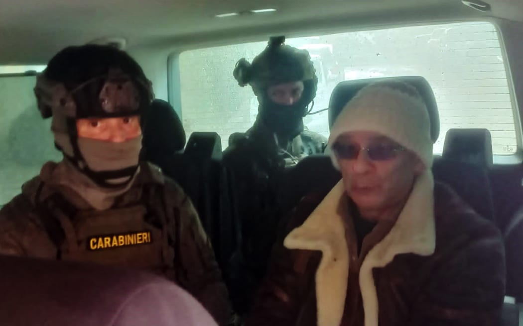 A police handout picture shows Italy's most-wanted mafia boss, Matteo Messina Denaro (R), being escorted in a vehicle by carabinieri after he was arrested in his native Sicily after 30 years on the run.