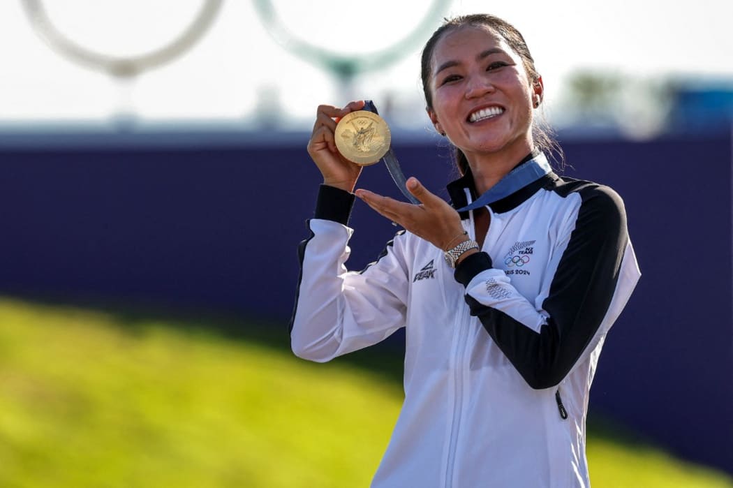 New Zealand's gold medallist Lydia Ko celebrates with her medal on the podium during the women’s golf individual stroke play medal ceremony of the Paris 2024 Olympic Games at Le Golf National in Guyancourt, south-west of Paris, on August 10, 2024. (Photo by Pierre-Philippe MARCOU / AFP)