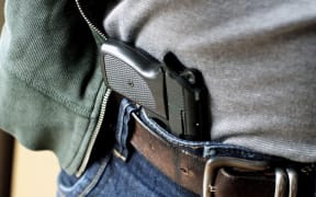 A gun concealed in a man's waistband.