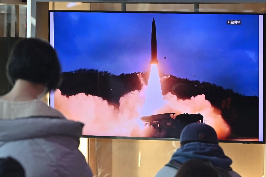 People watch a television screen showing a news broadcast with file footage of a North Korean missile test, at a railway station in Seoul on January 30, 2022, after North Korea fired a "suspected ballistic missile' in the country's seventh weapons test this month according to the South's military.