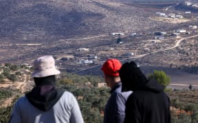 People look on towards Israeli settler outposts near the occupied West Bank village of Turmos Ayya on October 19, 2025. (Photo by HAZEM BADER / AFP)
