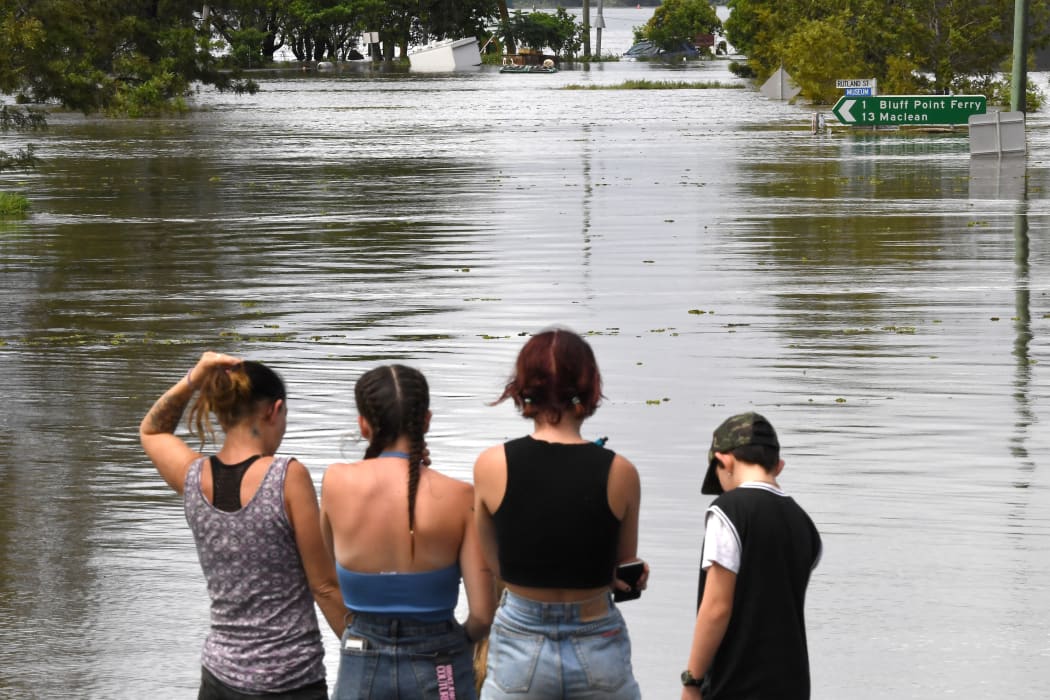 Residents stand by a flooded street in Lawrence suburb, some 70 kilometres New South Wales border city Lismore, on March 1, 2022. (Photo by SAEED KHAN / AFP)
