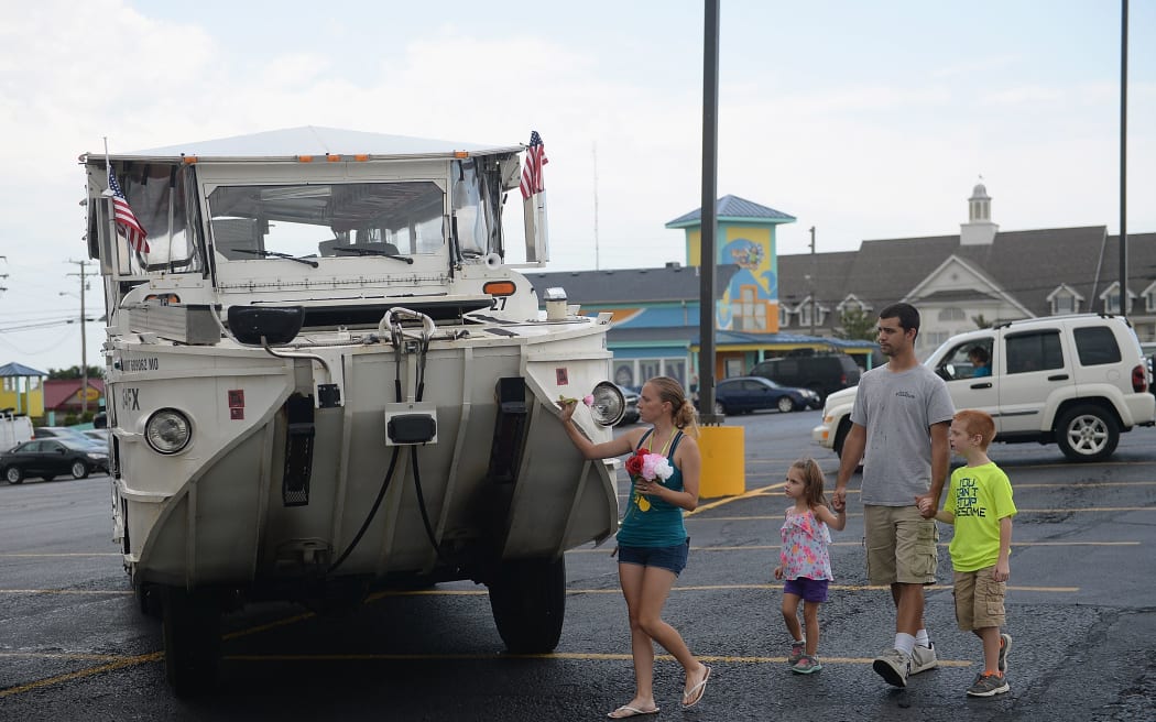 A family of mourners stop to place a flower on a World War II DUKW boat used by Ride The Ducks tours on July 20, 2018 in Branson, Missouri.