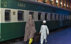 A woman and a child carry their bag as they arrive to board a train to Rawalpindi.