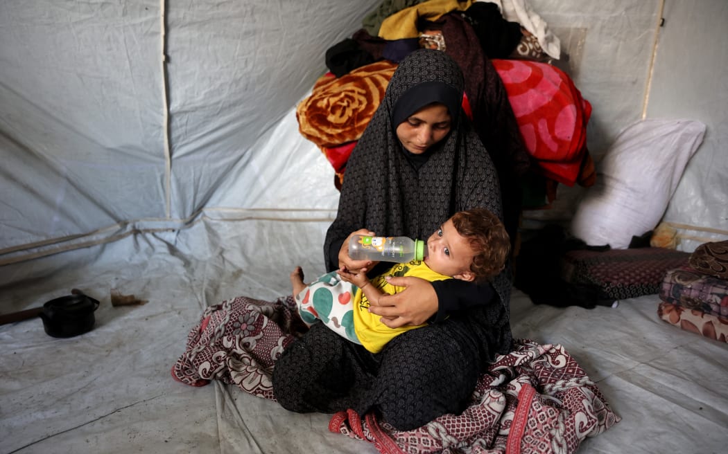 Khadija Sobh, 18 gives water to her seven-month daughter Janin Sobh inside their tent in the Daraj neighbourhood in Gaza City.