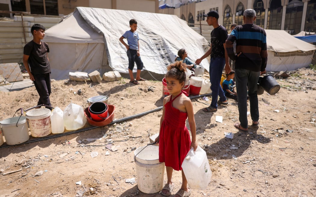 A girl holds plastic containers as displaced Palestinians collect water at a camp in Gaza City, on 20 May 2025, amid the ongoing war between Israel and the Palestinian militant movement Hamas.