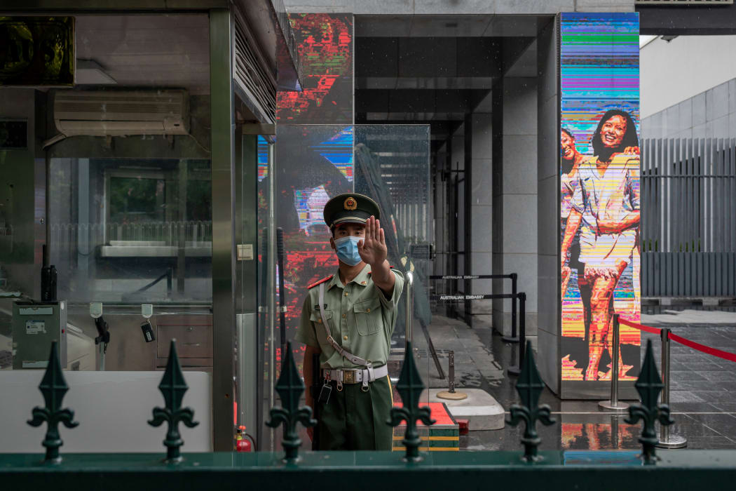 A Chinese paramilitary police officer gestures while standing at the entrance gate of the Australian embassy in Beijing on July 9, 2020.