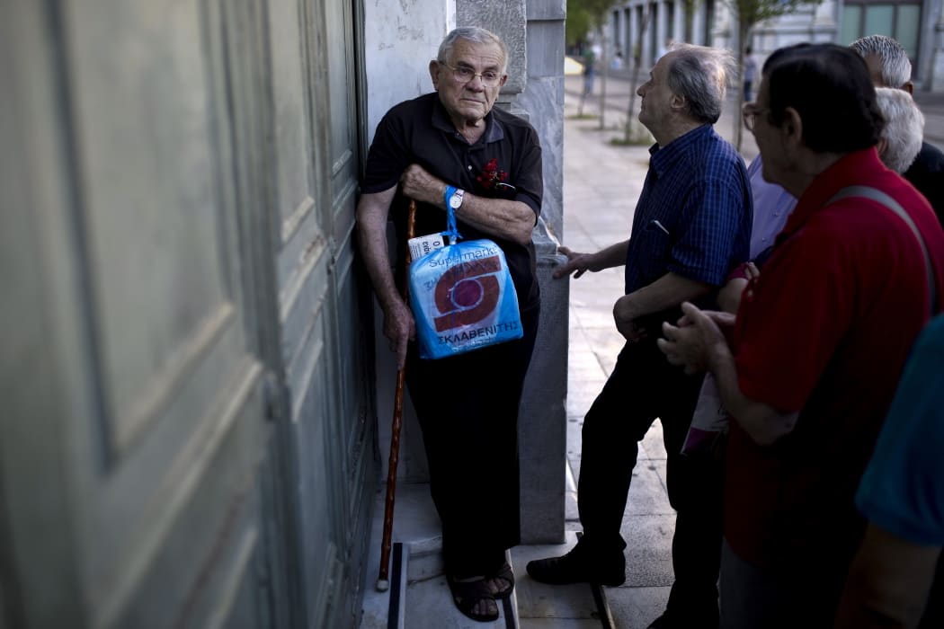 Pensioners wait outside a branch of the National Bank of Greece to receive their benefits, limited to €120, in Athens on 17 July 2015.