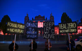 Climate activists hold illuminated signs and a banner protesting against the use of fossil fuels on the sidelines of the COP26 Climate Conference, at Kelvingrove in Glasgow, Scotland on November 3, 2021.