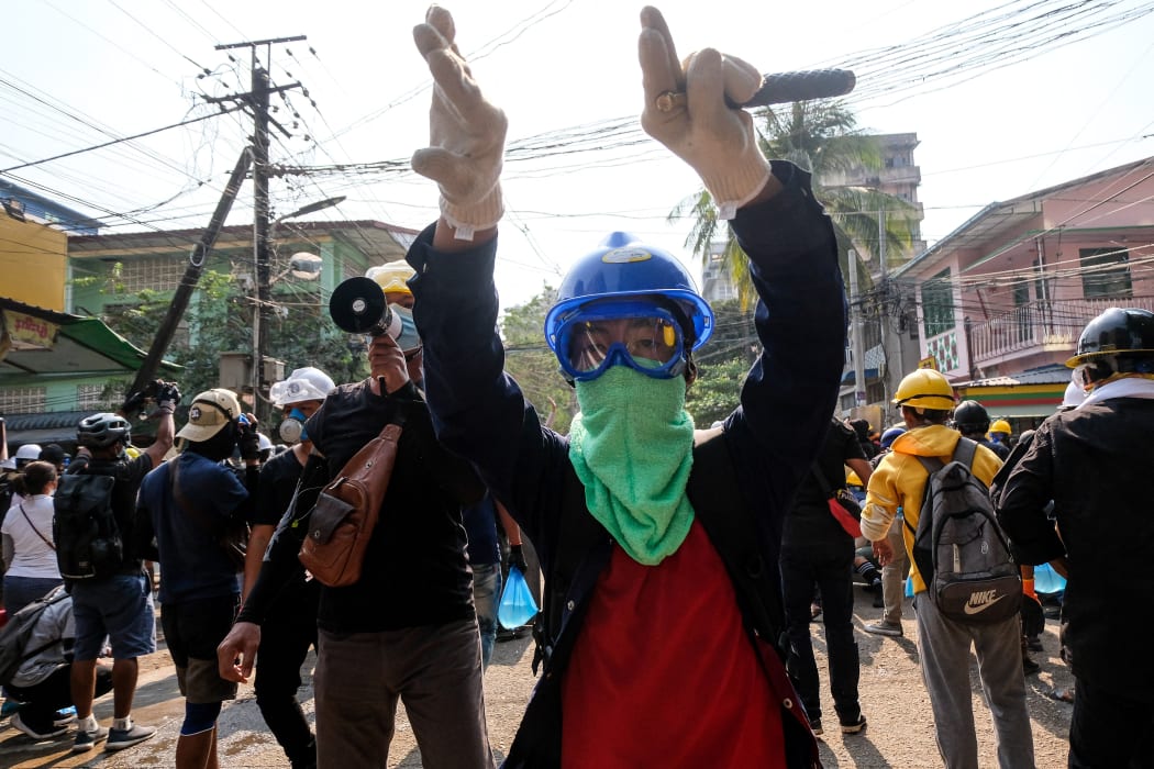 A protester gestures hand to move aside on path for protesters to run  during the riot force crackdown during an anti-coup protest in Yangon, yesterday.