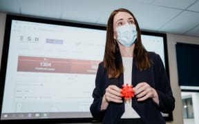 Prime Minister Jacinda Ardern wears a mask and holds a 3D model of the coronavirus during a visit to ESR in Porirua on 20 August 2020.