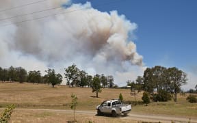 A car drives as a bushfire burns out of control in Hillville road near Taree, 350km north of Sydney on November 12
