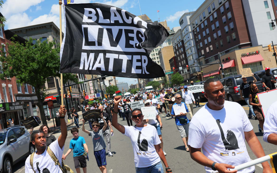 NEWARK, NEW JERSEY - JUNE 17: People march during a Juneteenth reparations rally on Broad Street on June 17, 2022 in Newark, New Jersey. The New Jersey Institute of Social Justice (NJISJ), elected officials, and activists marched and held a rally at City Hall celebrating the second year Juneteenth was recognized as a federal and state holiday in New Jersey. Legislation to make Juneteenth a federal holiday was introduced by Sen. Cory Booker (D-NJ) in 2020. Rally-goers also called on New Jersey lawmakers to pass legislation to establish a Reparations Task Force that would allow experts to study and propose targeted and strategic policy recommendations for reparative justice.   Michael M. Santiago/Getty Images/AFP (Photo by Michael M. Santiago / GETTY IMAGES NORTH AMERICA / Getty Images via AFP)