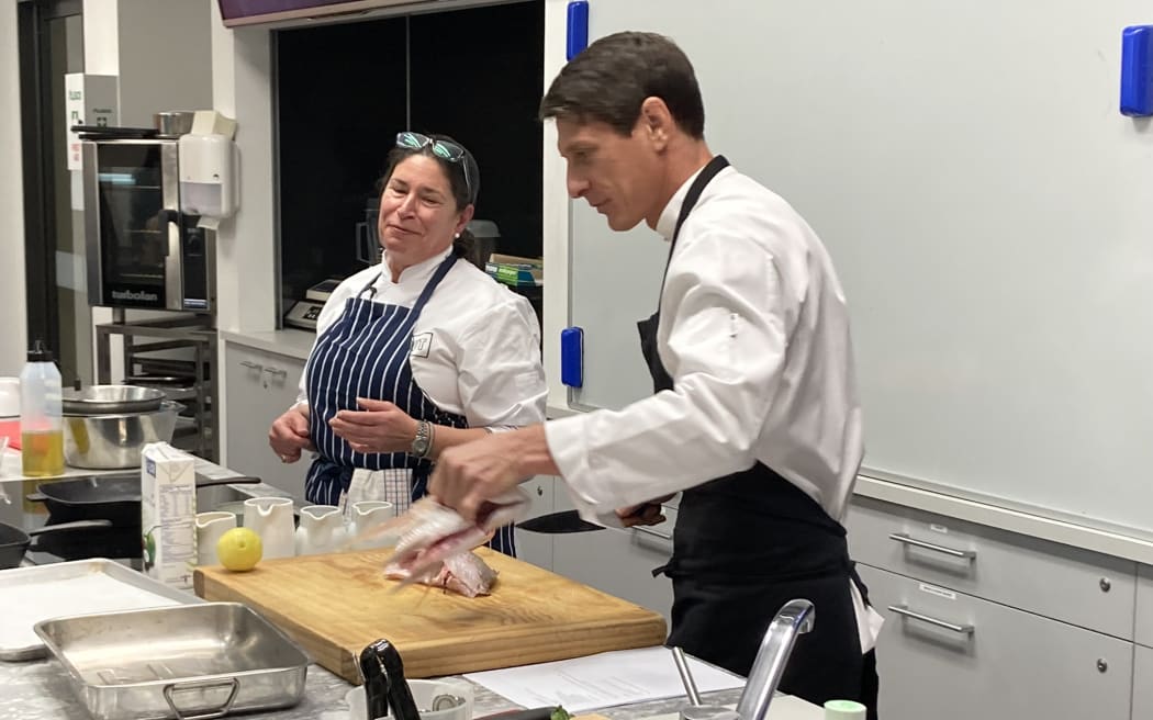 AUT professor of Food Studies Tracy Berno and New Caledonian chef Gaby Levionnois wearing chef aprons and cooking, during AUT's Culinary Arts and Gastronomy Winter Series 2022.