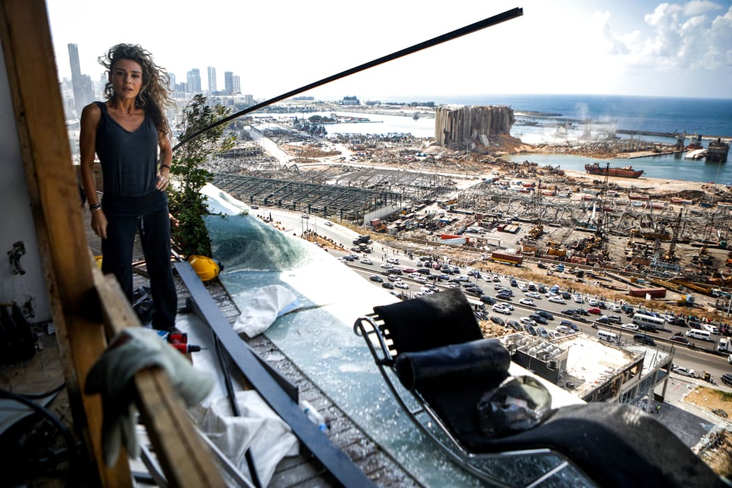 Karina Sukkar, a Lebanese architect and designer, stands on the balcony of her damaged apartment overlooking the ravaged port of Beirut.