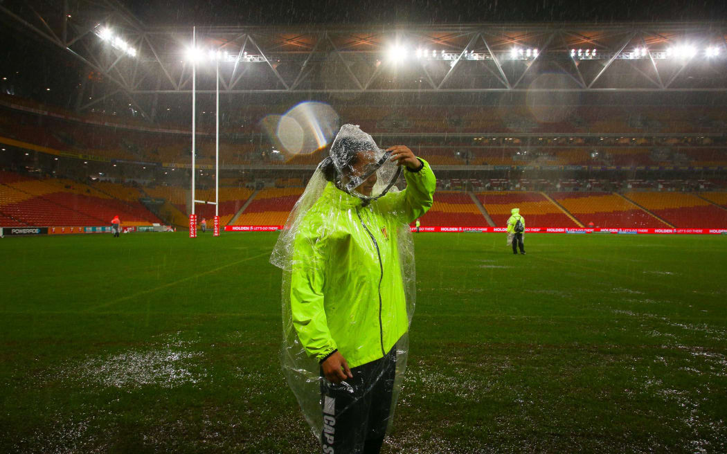 Security guards survey the sodden Suncorp Stadium ground
