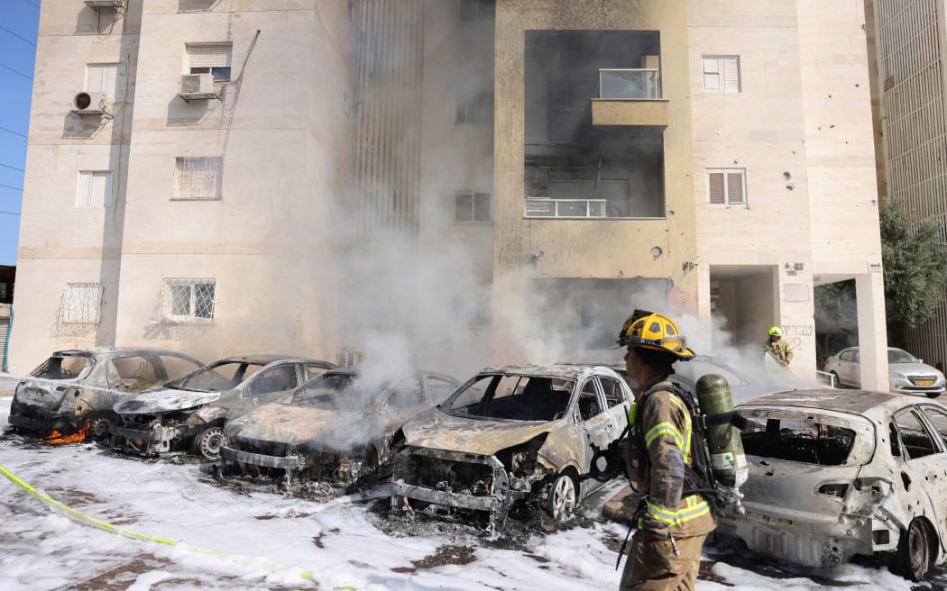 Israeli fire brigade teams douse the blaze in a parking lot outside a residential building following a rocket attack from the Gaza Strip in the southern Israeli city of Ashkelon, on October 7, 2023. Palestinian militants have begun a "war" against Israel, the country's defence miniser said on October 7 after a barrage of rockets were fired and fighters from the Palestinian enclave infiltrated Israel, a major escalation in the Israeli-Palestinian conflict. (Photo by AHMAD GHARABLI / AFP)