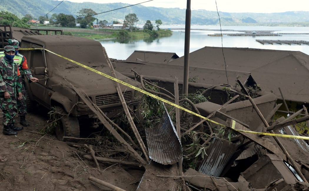 Military personnel (L) work at the scene of a landslide triggered by a 4.8 magnitude earthquake at Trunyan village in Bangli, Indonesia's Bali island, on October 16, 2021.