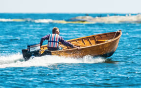 man driving motorboat, lifejacket