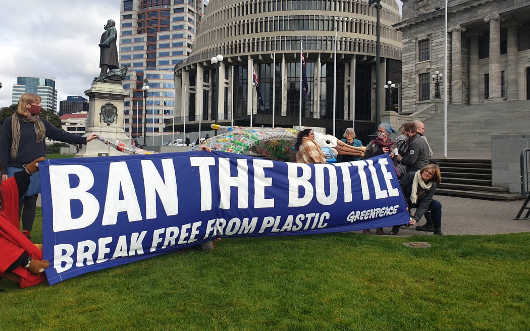 Greenpeace presented a petition to Green MP Eugenie Sage signed by 100,000 people calling on the government to ban single-use plastic bottles. A sculpture of a bird made of reclaimed plastic bottles stands behind a Greenpeace banner.