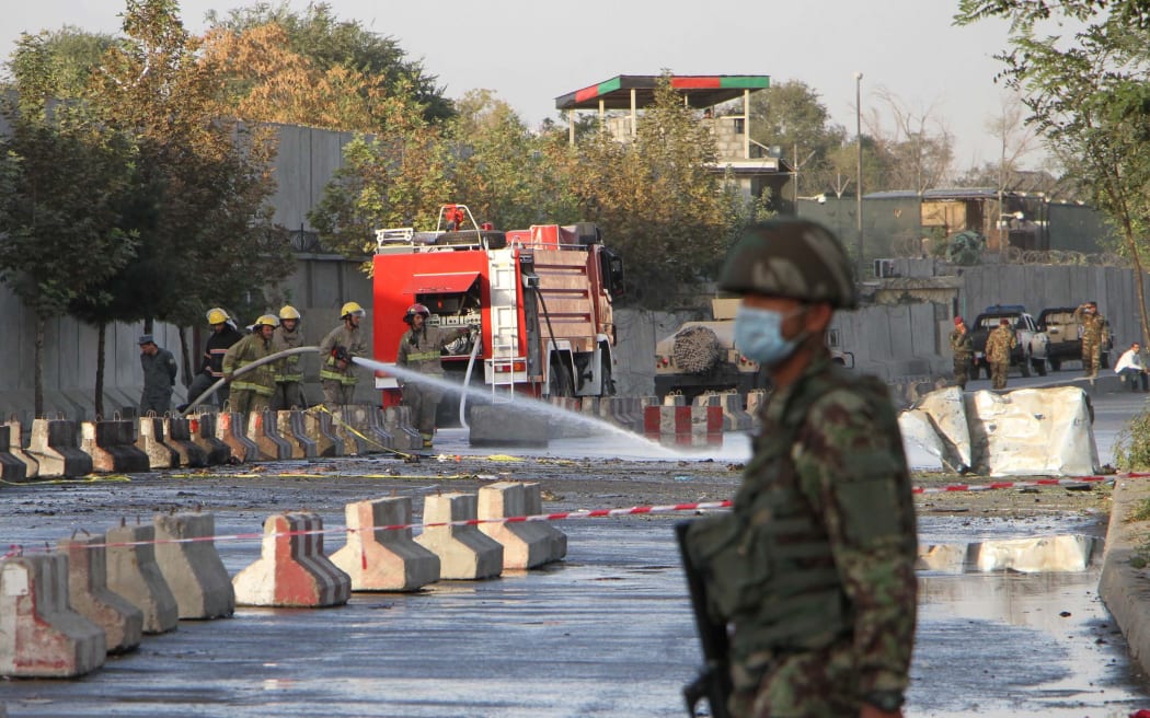 Afghan security forces stand by as the area where two blasts killed at least 24 people in Kabul is cleared.