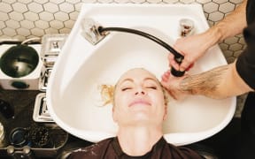 [Utah, USA] A female client at a hair salon, having her hair rinsed in a basin. (Photo by Mint Images / Mint Images / Mint Images via AFP)