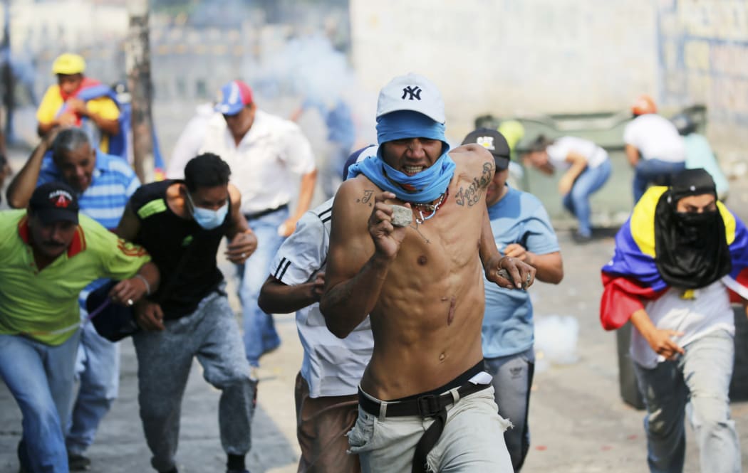 Demonstrators run from tear gas fired by Bolivarian National Guard officers during clashes in Urena, Venezuela, near the border with Colombia, Saturday, Feb. 23, 2019.