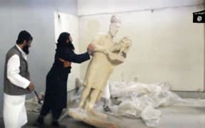 An image grab taken off a video by Islamic State allegedly shows a militant pushing a statue inside the Mosul museum.