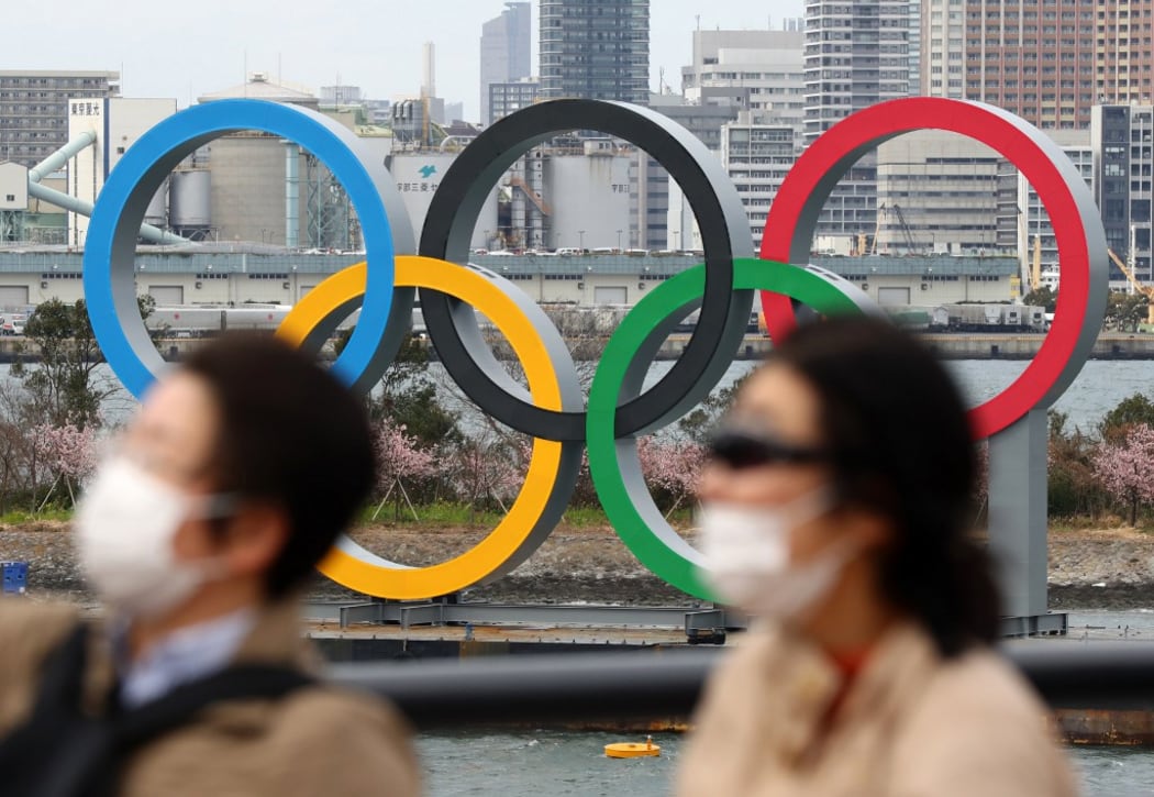 People wearing a mask walk near the Olympics' mark in Odaiba, Tokyo, amid the outbreak of a new coronavirus in Japan.
