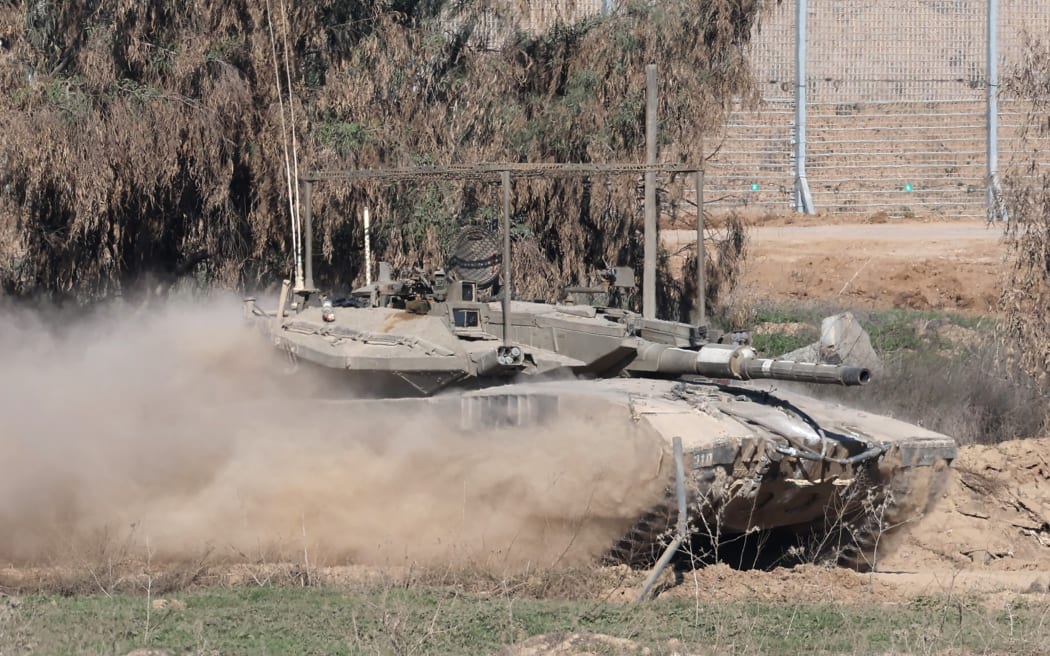 A picture taken from a position in southern Israel along the border with the Gaza Strip shows a tank rolling on December 29, 2023, amid continuing battles between Israel and the militant group Hamas. (Photo by JACK GUEZ / AFP)