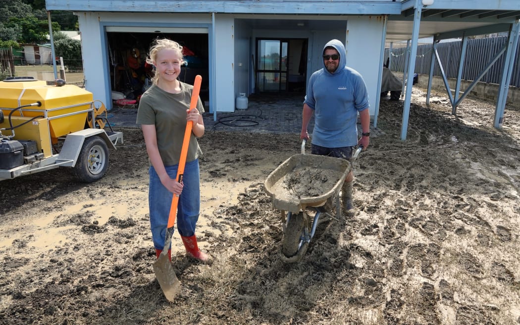 Mark and Victoria Seymour, 13, work to clean up the sticky, stinky silt that has engulfed the long-time family bach.