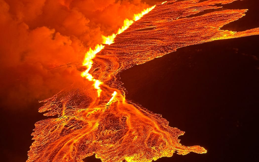 This handout picture released by the Icelandic Coast Guard on March 16, 2024 shows billowing smoke and flowing lava pouring out of a new fissure during a new volcanic eruption on the outskirts of the evacuated town of Grindavik, western Iceland. A volcanic eruption started on the Reykjanes peninsula in southwestern Iceland on Thursday, the third to hit the area since December, authorities said. (Photo by HANDOUT / Icelandic Coast Guard / AFP) / RESTRICTED TO EDITORIAL USE - MANDATORY CREDIT "AFP PHOTO /HANDOUT/ICELANDIC COAST GUARD " - NO MARKETING - NO ADVERTISING CAMPAIGNS - DISTRIBUTED AS A SERVICE TO CLIENTS