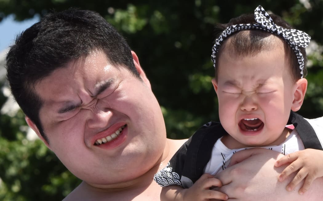 A baby held by a student sumo wrestler cries during a competition at Sensoji Temple in Tokyo on Saturday.