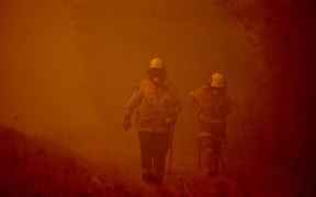 Firefighters tackle a bushfire in thick smoke in the town of Moruya, south of Batemans Bay, in New South Wales on January 4, 2020.