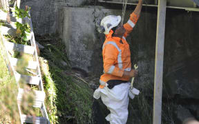 Fulton Hogan service person Tamati Teohera works to repair a broken water main on Nelson Road that has left 51 properties without water.