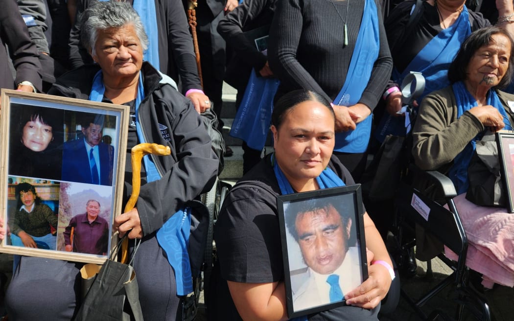 Whānau on the steps of Parliament with photos of their loved ones.