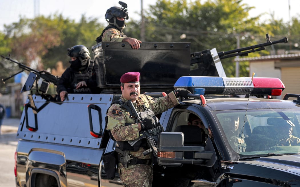 Fighters of Iraq's Hashed al-Shaabi (Popular Mobilisation Forces - PMF) paramilitaries ride in vehicles moving in a convoy during the funeral of Hassan Hammadi al-Amiri, a fallen member of the group Kataeb Hezbollah, one of the factions of the PMF, in Baghdad on December 26, 2023, after he was killed earlier in a US airstrike. US air strikes targeting a pro-Iranian group in Iraq on December 26 claimed at least one life, drawing an angry response from Baghdad as regional tensions spike amid the Israel-Hamas war. The United States has repeatedly targeted sites used by Iran and its proxy forces in Iraq and Syria in response to dozens of attacks on American and allied forces in the region since the October 7 outbreak of the war. (Photo by AHMAD AL-RUBAYE / AFP)