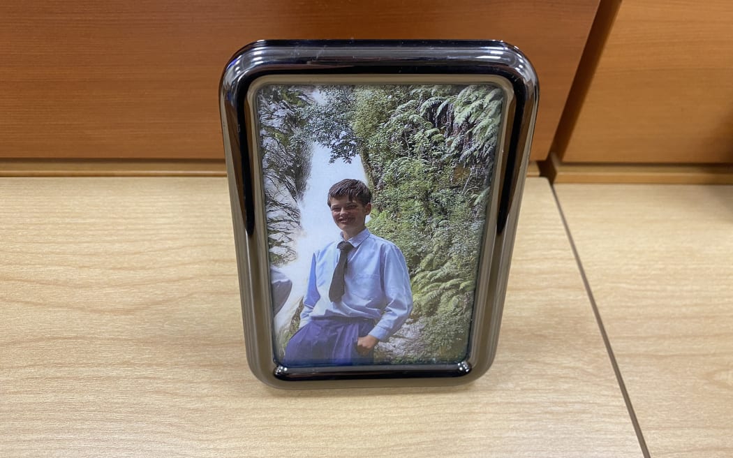 Sincere Standtrue, pictured standing on the edge of a waterfall in his Gloriavale uniform, was placed at the front of the courtroom on the first day of the inquest into his death in 2018.