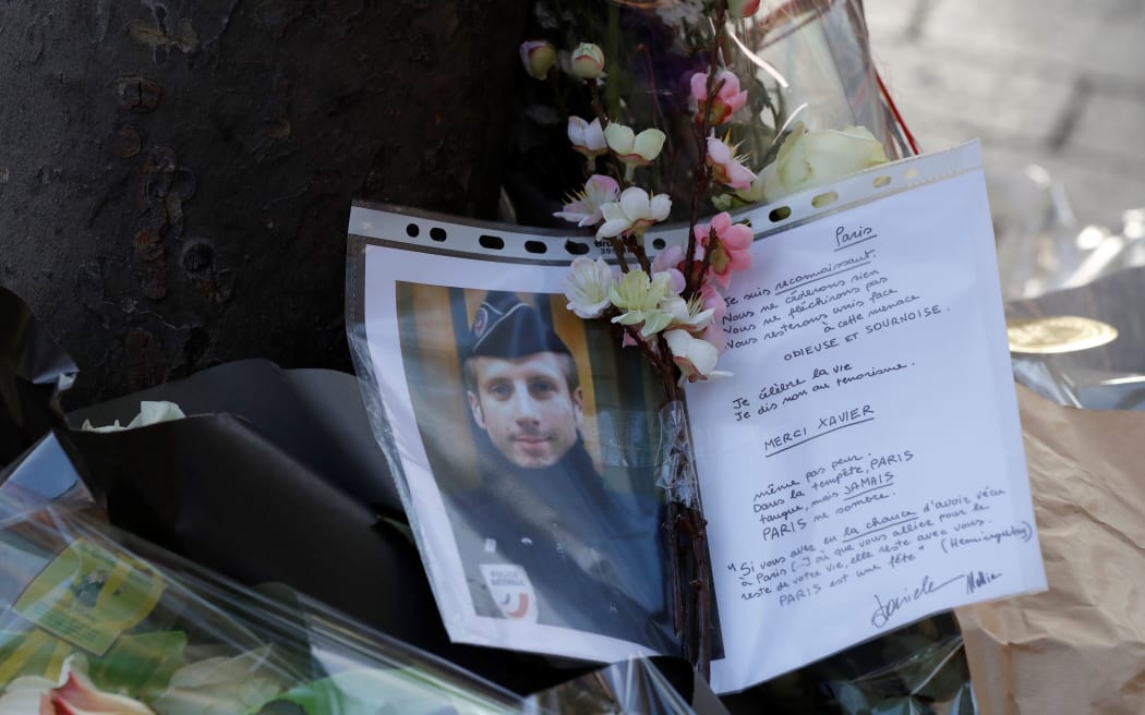 A picture taken on April 21, 2017 in Paris shows a photo and a letter displayed at the site of a shooting on the Champs Elysees