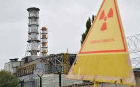 A sign warning of radiation near a shelter and containment area built at Chernobyl's old nuclear power plant.