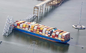 BALTIMORE, MARYLAND - MARCH 26: In an aerial view, the cargo ship Dali sits in the water after running into and collapsing the Francis Scott Key Bridge on March 26, 2024 in Baltimore, Maryland. According to reports, rescuers are still searching for multiple people, while two survivors have been pulled from the Patapsco River. A work crew was fixing potholes on the bridge, which is used by roughly 30,000 people each day, when the ship struck at around 1:30am on Tuesday morning. The accident has temporarily closed the Port of Baltimore, one of the largest and busiest on the East Coast of the U.S.   Tasos Katopodis/Getty Images/AFP (Photo by TASOS KATOPODIS / GETTY IMAGES NORTH AMERICA / Getty Images via AFP)