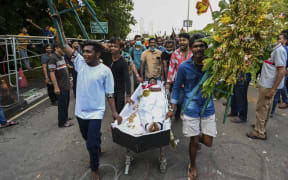 University students push a coffin with a demonstrator dressed as Sri Lanka's Prime Minister Mahinda Rajapaksa during a demonstration demanding his resignation.