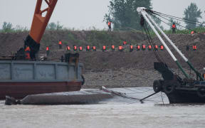 Rescue workers can be seen next to the capsized boat on 3 June.