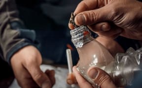 A man smokes drugs through a Bong bottle, a way of using cannabis