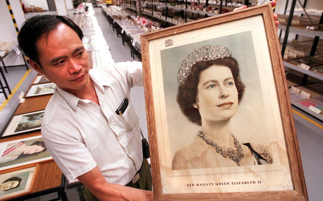 Senior Supplies Supervisor Lin Pong-yin holds up a stained portrait of Queen Elizabeth II 17 October,  which was among nearly 10,000 items bearing connotations of British sovereignty that were to be auctioned to the public.