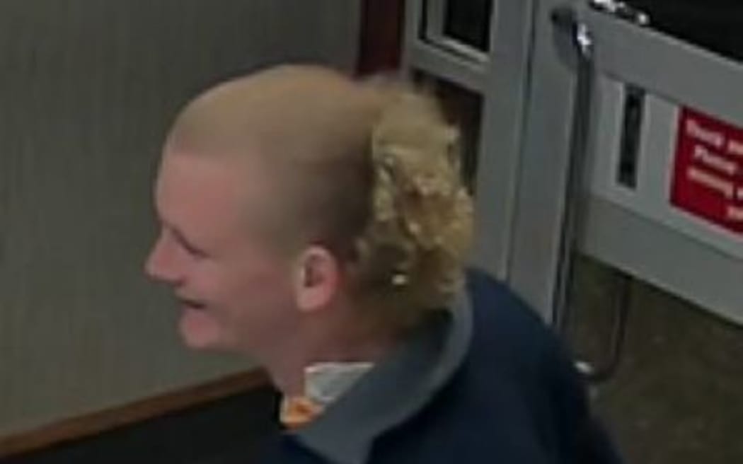 A man with blonde hair, light skin tone, wearing a navy blue jacket.