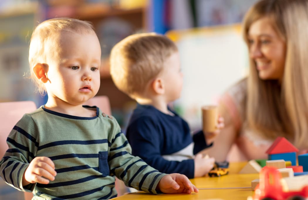 Nursery babies playing blocks toy with teacher in kindergarten